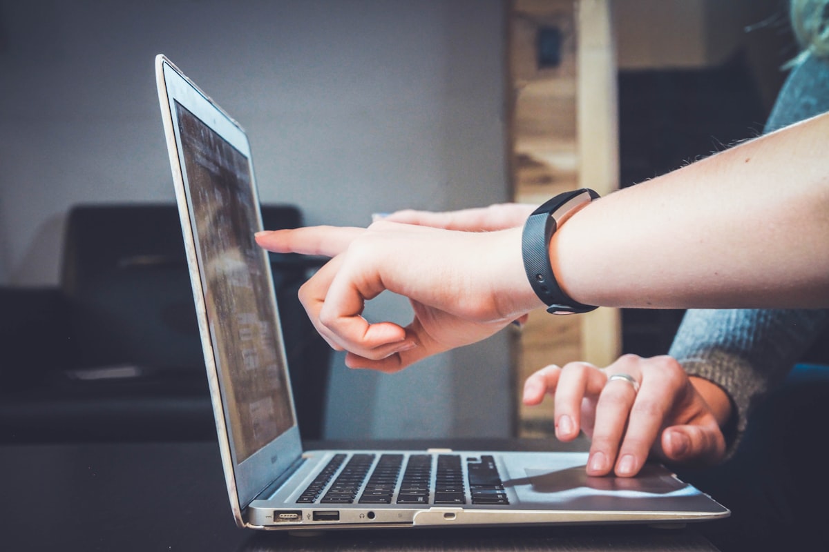 Hands typing on a silver laptop at a tidy desk